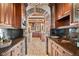 Gourmet kitchen featuring stone floors, wooden cabinets, granite countertops, and a stone archway at 2 University Ln, Greenwood Village, CO 80121