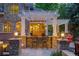 Outdoor kitchen beneath a pergola, featuring a stone bar, seating, and integrated lighting at 2 University Ln, Greenwood Village, CO 80121