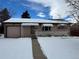 Ranch style home with attached garage and snow-covered front yard at 1851 S Perry Way, Denver, CO 80219