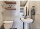 Stylish half-bath with pedestal sink, modern fixtures, floating shelves, and neutral wall color at 16364 Flintlock Ct, Parker, CO 80134