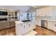 Open concept kitchen with white cabinets, island cooktop, and adjacent living area with fireplace at 16364 Flintlock Ct, Parker, CO 80134