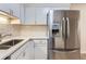 Kitchen showcasing a stainless steel refrigerator and sink with sleek countertops and white cabinets at 3315 S Ammons St # 103, Lakewood, CO 80227