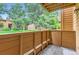 Private balcony with wooden railing offers a peaceful outdoor retreat and views of mature trees and the lawn at 3315 S Ammons St # 103, Lakewood, CO 80227