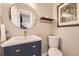 Powder bathroom with round mirror and gold accents, with a peek into a staircase through the doorway at 76 S Garfield St, Denver, CO 80209