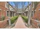 Picturesque courtyard featuring Tudor-style townhomes, brick walkways, mature trees, and manicured hedges at 76 S Garfield St, Denver, CO 80209