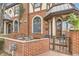 Charming Tudor-style townhome with a cozy patio, brick wall, wrought iron gate, and lush landscaping at 76 S Garfield St, Denver, CO 80209