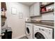 Bright laundry room featuring a white washer and dryer and cabinets and floating shelves for extra storage at 8204 S Vandriver Way, Aurora, CO 80016