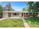 Charming brick home with a manicured lawn and a classic picket fence, showcasing a welcoming curb appeal at 8675 W 60Th Ave, Arvada, CO 80004
