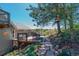 Wooden deck area with outdoor dining set, overlooking natural landscape with stone pathway and mature trees at 1549 Hillside Cir, Sedalia, CO 80135