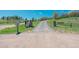 Long private driveway leading to the home, passing a gated entry and a mailbox on lush green grass at 1549 Hillside Cir, Sedalia, CO 80135