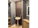 Stylish powder room featuring a pedestal sink with gold fixtures and a unique tiled accent wall at 18963 E Long Ave, Centennial, CO 80016