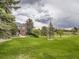 Spacious front yard featuring mature trees, lush lawn, and a classic brick home with elegant architectural details at 18963 E Long Ave, Centennial, CO 80016