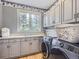 Well-lit laundry room with ample cabinet space, washer, dryer, and large window at 18963 E Long Ave, Centennial, CO 80016