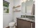 Bathroom featuring wood shelves, a mirror and vanity with granite countertop and dark wood cabinets at 1754 W 66Th Ave, Denver, CO 80221