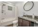 Bright bathroom features a shower-tub combo, granite countertop, wood cabinets, and updated fixtures at 1754 W 66Th Ave, Denver, CO 80221