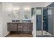 Bathroom featuring dual sinks, blue subway tile in a glass shower and dark wood cabinets at 1754 W 66Th Ave, Denver, CO 80221