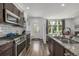 A modern kitchen with stainless steel appliances, dark wood cabinets, island and an adjacent living space at 1754 W 66Th Ave, Denver, CO 80221