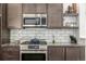 Modern kitchen features stainless steel appliances, subway tile backsplash and dark wood cabinets at 1754 W 66Th Ave, Denver, CO 80221