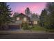 Charming two-story home featuring stone accents, a well-manicured lawn, and mature trees at dusk at 1973 S Pitkin St, Aurora, CO 80013