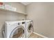 This laundry room includes a washer and dryer, shelf, and neutral-toned tile flooring at 22021 Pebble Brook Ln, Parker, CO 80138