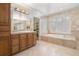 Well-lit primary bathroom with dual sinks, vanity storage, large mirror, soaker tub and neutral tiling at 100 S University Blvd # 11, Denver, CO 80209