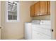 Practical laundry room with washer, dryer, upper cabinets, and a window for natural light at 100 S University Blvd # 11, Denver, CO 80209