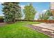 Spacious backyard featuring a large, well-maintained lawn, mature trees, and patio at 5262 E Sandpiper Ave, Castle Rock, CO 80104