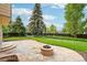 Outdoor stone patio with fire pit, lawn, and mature landscaping creates the perfect private oasis at 5262 E Sandpiper Ave, Castle Rock, CO 80104