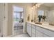 Bright bathroom with dual sink vanity, large mirror and view into main bedroom at 6807 Huddersfield Ln, Castle Pines, CO 80108