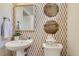 Stylish powder room features pedestal sink, decorative wall art and warm color scheme at 6807 Huddersfield Ln, Castle Pines, CO 80108