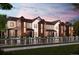 Modern townhome complex with diverse color schemes and covered entrances reflecting in the wet street at 6807 Huddersfield Ln, Castle Pines, CO 80108