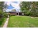Spacious backyard with green grass, brick house, covered patio, and a cozy fire pit at 1646 S Stuart St, Denver, CO 80219