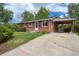 Red brick home with carport and concrete driveway and beautiful landscaping at 1646 S Stuart St, Denver, CO 80219