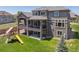 Spacious backyard with a two-story deck/balcony, lush lawn, and playground at 14022 E Fair Pl, Centennial, CO 80111