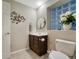 Modern half bath with a dark wood cabinet and a stylish, decorative round mirror at 1497 Bent Grass Cir, Castle Rock, CO 80109