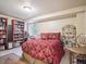 Cozy bedroom featuring a red patterned comforter, bookshelves, and natural light from the window at 4151 S Lewiston Cir, Aurora, CO 80013