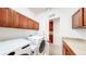 Functional laundry room with modern appliances, cherry-stained cabinets, and lots of space at 14230 Lakeview Ln, Broomfield, CO 80023