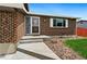 A welcoming entrance to the brick home with a concrete walkway and lush landscaping at 7350 Devinney Ct, Arvada, CO 80005