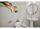 Stylish powder room features a pedestal sink, round mirror, neutral color palette, and geometric wall art at 1793 W 166Th Ave, Broomfield, CO 80023