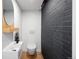 Modern powder room with a stylish floating sink, round mirror, and a painted brick accent wall at 2060 Hoyt St, Lakewood, CO 80215