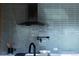 Modern kitchen featuring subway tile backsplash, stainless vent hood, and black faucet at 2060 Hoyt St, Lakewood, CO 80215