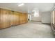 Open basement area with wood paneled walls and carpet flooring at 7475 W Vassar Ave, Lakewood, CO 80227