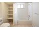 Bright bathroom with white tile, open shelves for storage, and a shower/tub combo at 7475 W Vassar Ave, Lakewood, CO 80227