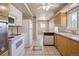 Traditional kitchen features tile floor, white appliances, light wood cabinets and a ceiling fan at 7475 W Vassar Ave, Lakewood, CO 80227