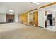 Spacious living room features a brick fireplace, carpet, and an adjacent kitchen at 7475 W Vassar Ave, Lakewood, CO 80227