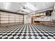 Open garage featuring large door, checkered tile floors, and ample storage shelving at 8881 Lilly Dr, Thornton, CO 80229