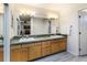 Bright bathroom featuring dual sinks, wood cabinets and a large, well-lit mirror at 8394 S Everett Way # E, Littleton, CO 80128