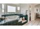 Soaking tub with green tile surround features wooded views and plenty of natural light at 6335 Oberon Rd, Arvada, CO 80004