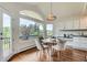 Sun-filled dining area features hardwood floors, large windows with wooded views, and decorative lighting at 6335 Oberon Rd, Arvada, CO 80004