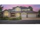 Charming two-story home with a brick facade, gray roof, lush landscaping, and a three-car garage at 6335 Oberon Rd, Arvada, CO 80004